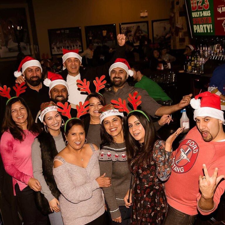 Group of customers at a holiday party at The Canadian Brewhouse wearing reindeer antlers and Santa hats