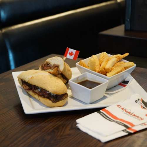 The Canadian Brewhouse Beef Dip with a side of fries, displayed on a booth table.