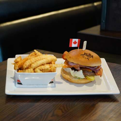 The Canadian Brewhouse Canadian Burger with a side of fries, displayed on a booth table.